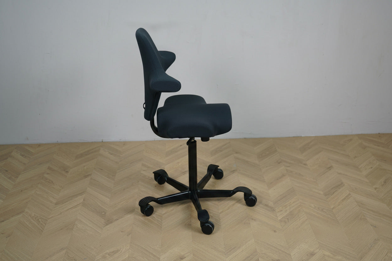 HÅG Capisco 8106 set fra siden med ergonomisk sadelsæde, justerbart ryglæn, sort aluminiumsfodkryds og gummibanehjul.