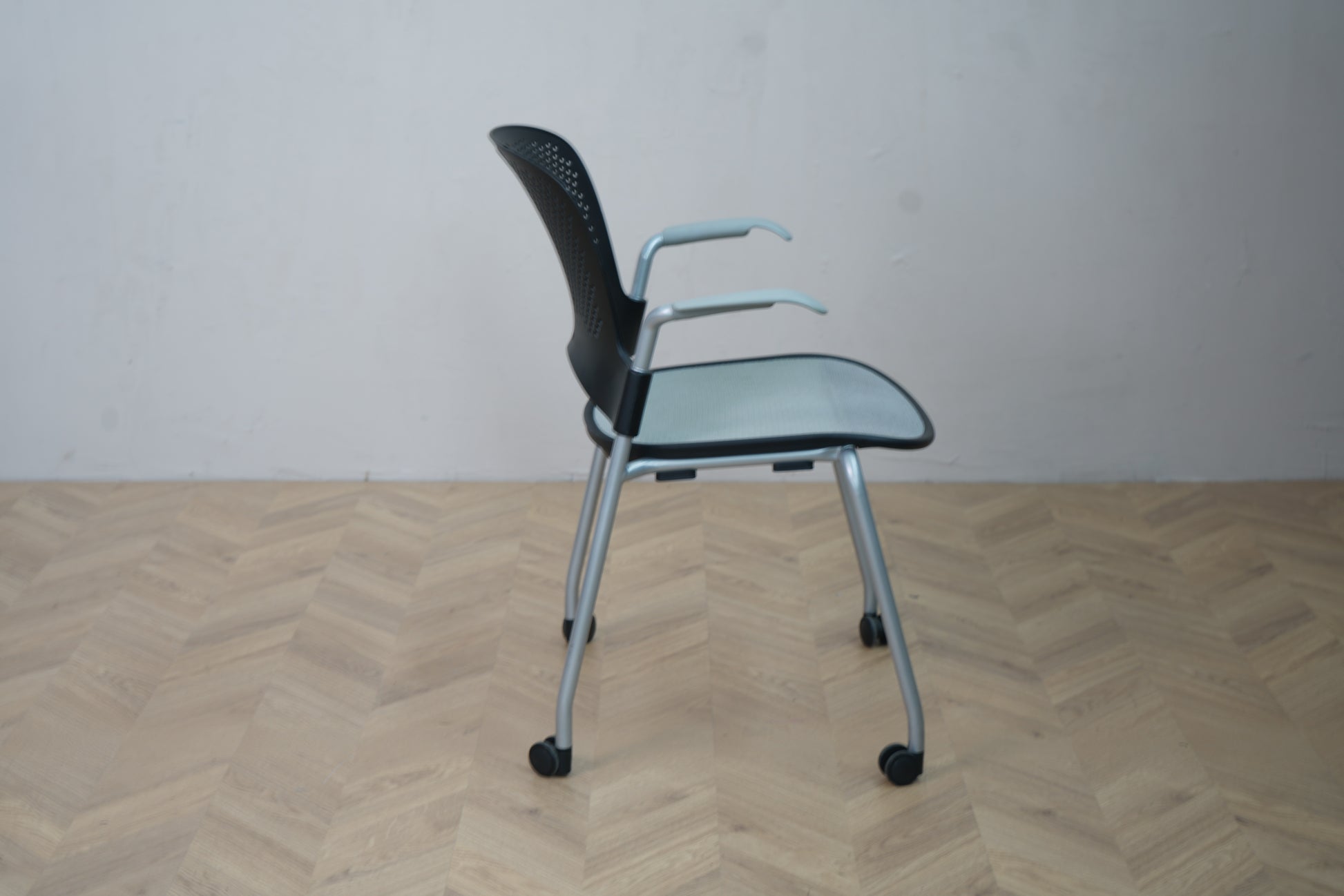 Herman Miller Casper konferencestol med hjul set fra siden, viser armlæn, buet ryglæn og metalstel med hjul.