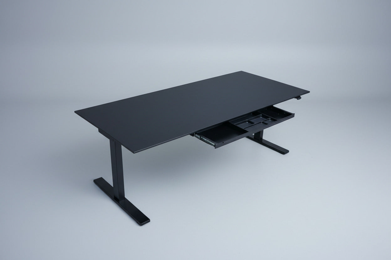 Holmris B8 hæve-sænkebord set skråt med sort linoleumsbordplade og integreret skuffe