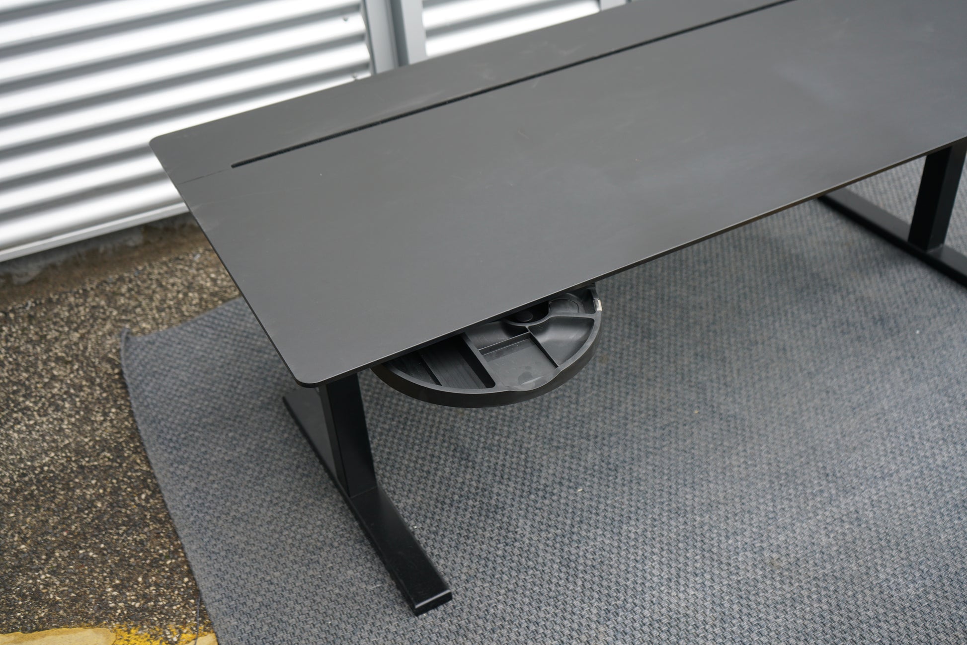 Holmris B8 hæve-sænkebord set oppefra med sort bordplade, kabelgennemføring og integreret opbevaringsskuffe.