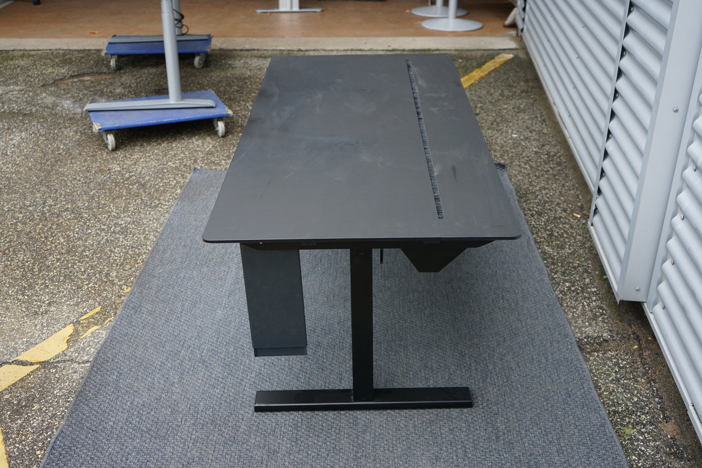 Holmris B8 hæve-sænkebord set fra siden i sort med justerbart stel, skuffe og kabelstyring, 180x80 cm skrivebord.