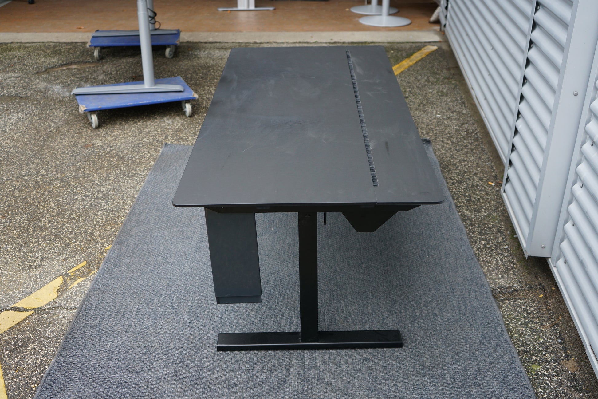 Holmris B8 hæve-sænkebord set fra siden i sort med justerbart stel, skuffe og kabelstyring, 180x80 cm skrivebord.