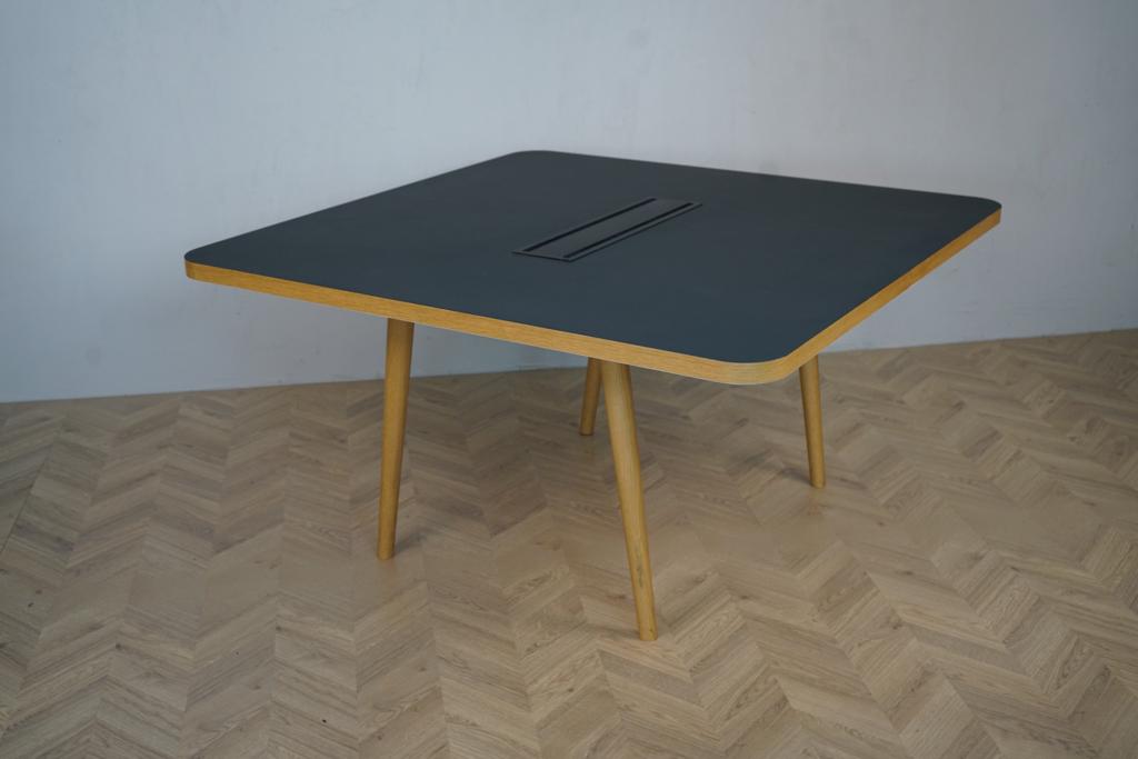 Forum-bord 140x140 cm fra Icons of Denmark i sort linoleum med egetræskant og ben – set skråt forfra