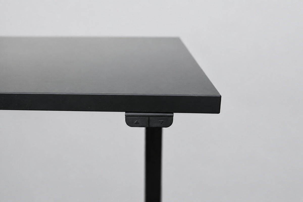 Close up af IKEA hæve-sænkebord med sort laminatbordplade og sort stel