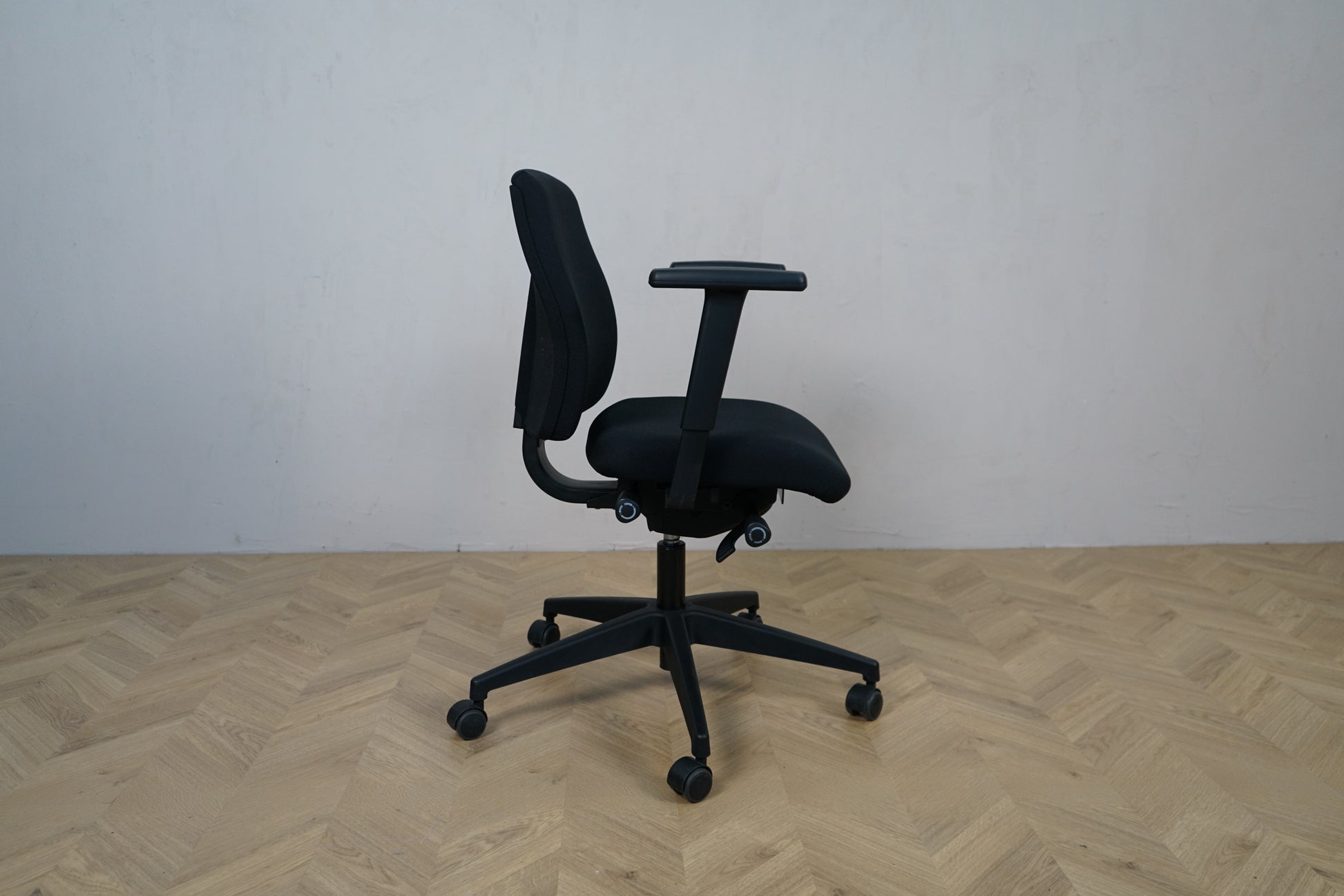 Interstuhl sort kontorstol med armlæn set bagfra.