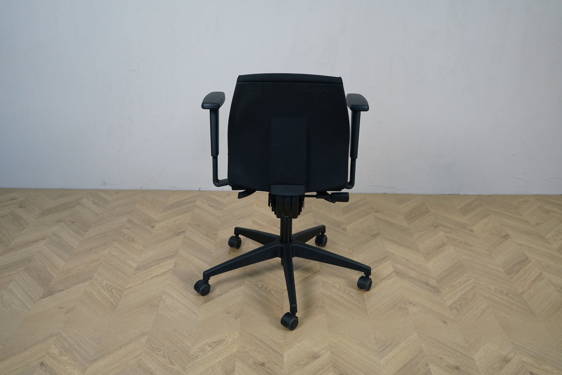 Close-up af sæde og betræk på Interstuhl sort kontorstol med armlæn.