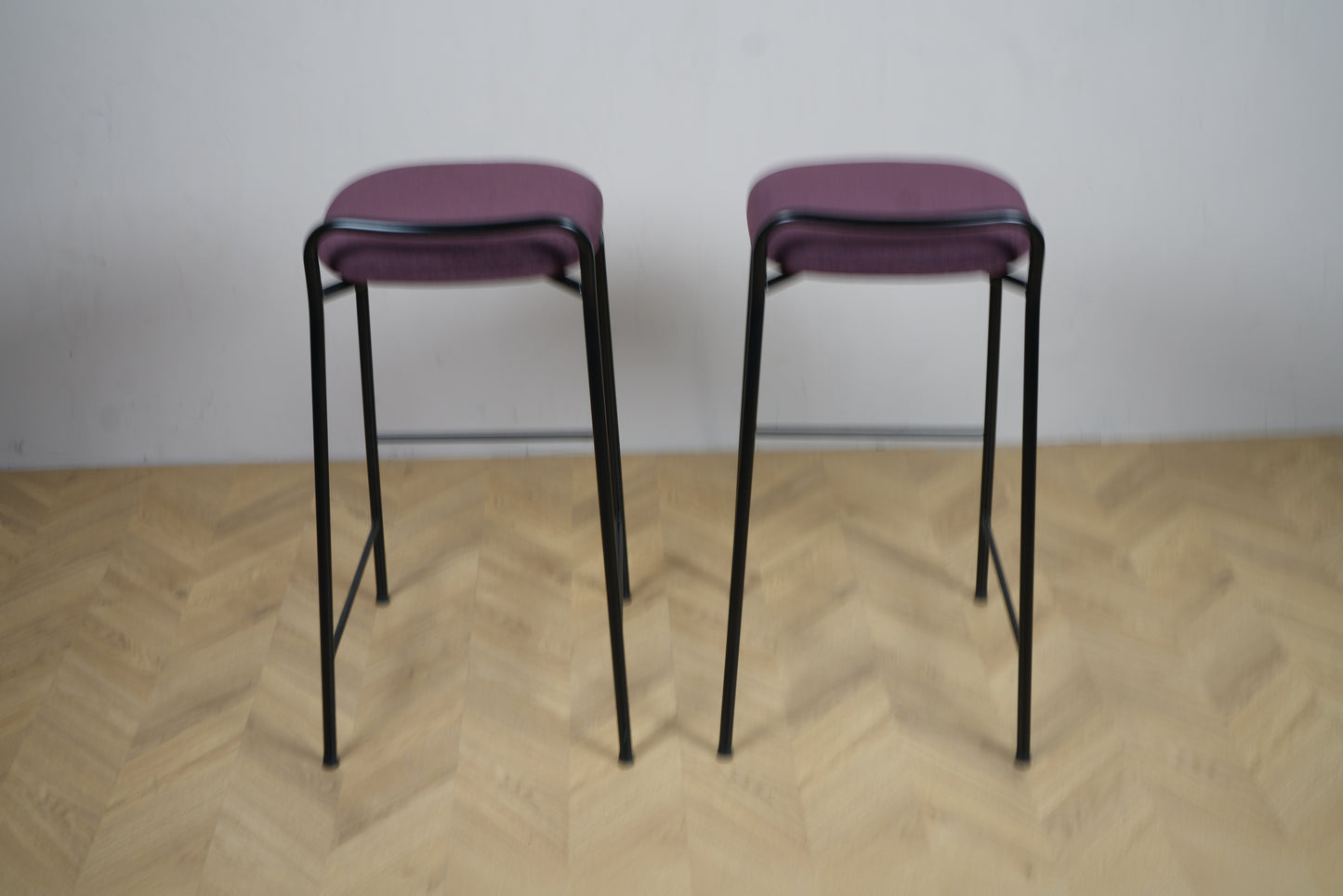 To Kinnarps barstole i lilla stof med sort stel set bagfra
