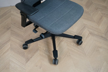 Close up af Kinnarps Capella kontorstol i mørkegrå med polstret sæde og armlæn