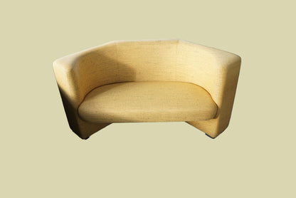 Kinnarps gul sofa med afrundet design og struktureret møbelstof, set forfra.