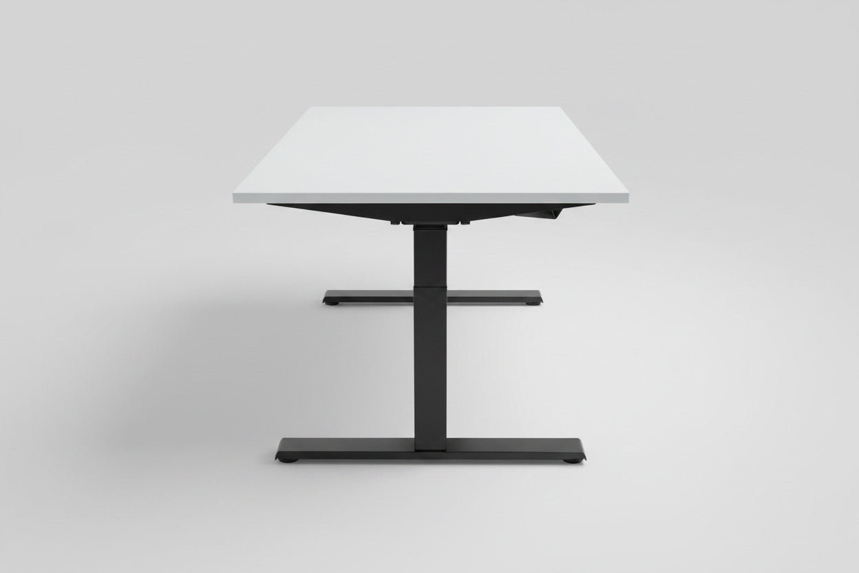 Kinnarps hæve-sænkebord 140x80 cm set fra siden med hvid laminatbordplade, sort stel og sort kabelbakke.