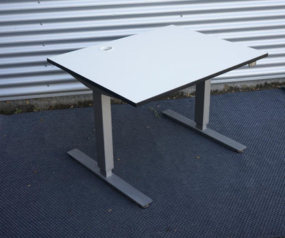 Kinnarps hæve-sænkebord i hvid set i skrå vinkel. Elektrisk hæve-sænkebord med kompakt bordplade 100x80 cm, perfekt til små arbejdspladser.