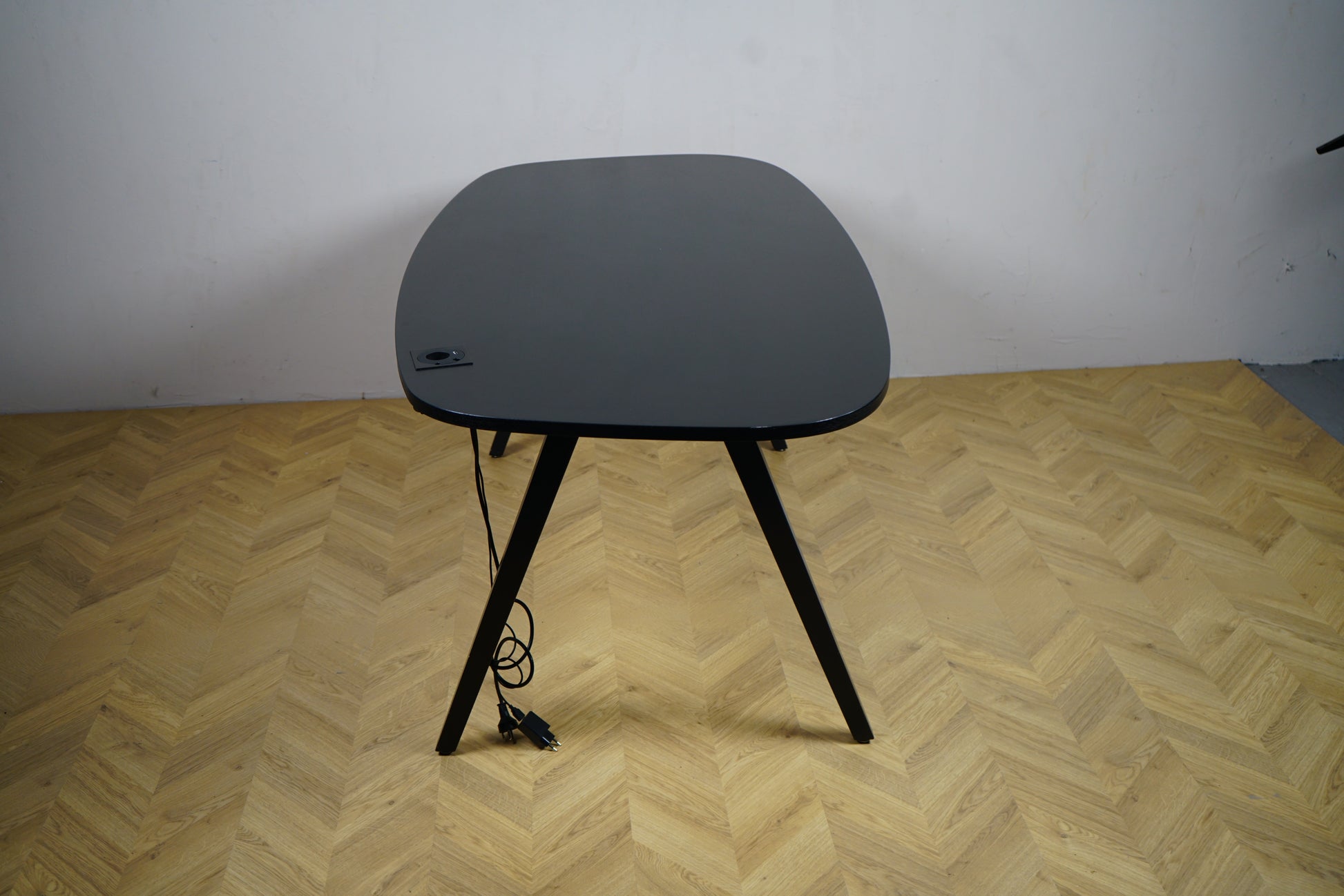 Kinnarps Oberon sort skrivebord set fra siden – stilrent og funktionelt skrivebord med integreret strømudtag og solid konstruktion.