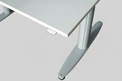 Close-up af hvid laminatbordplade og metaldetaljer på Kinnarps T-Serie hæve-sænkebord.