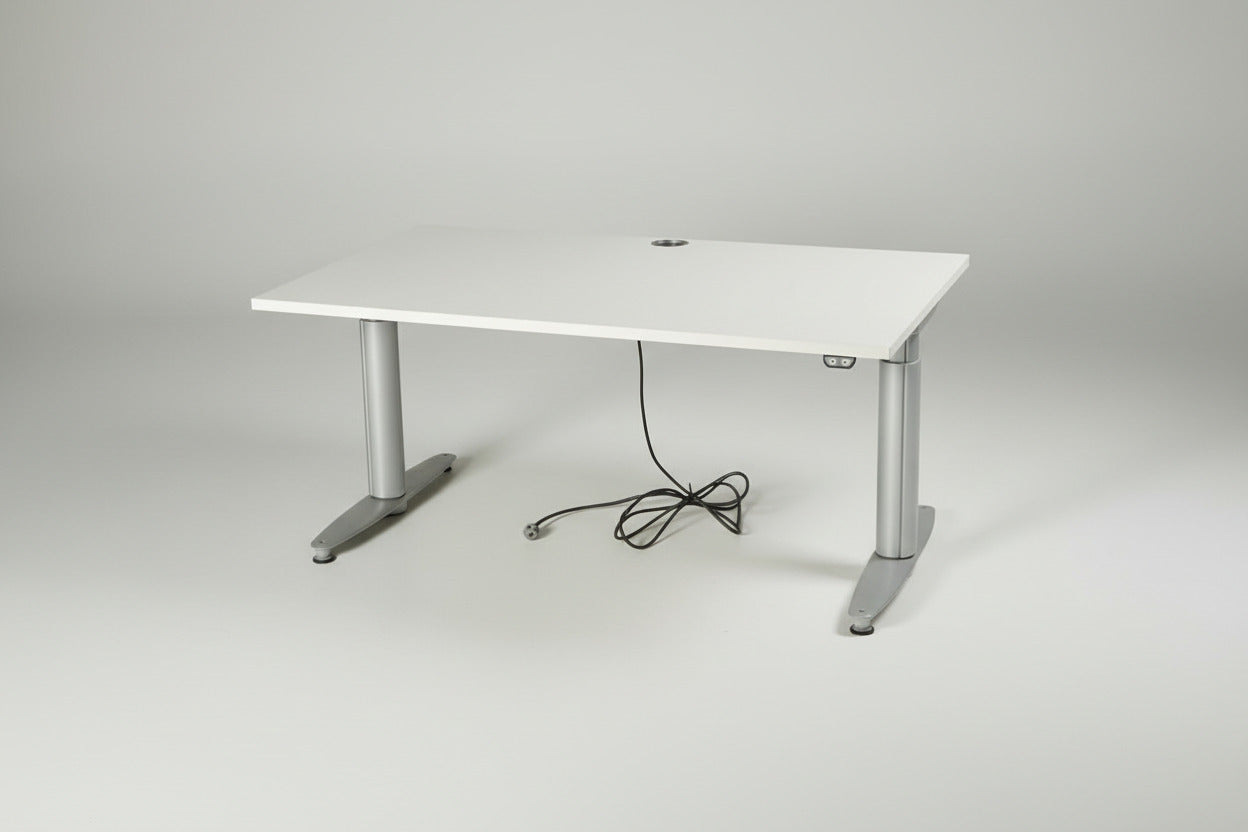Kinnarps T-Serie hæve-sænkebord i hvid laminat set forfra med robuste metalsøjler og ergonomisk design.