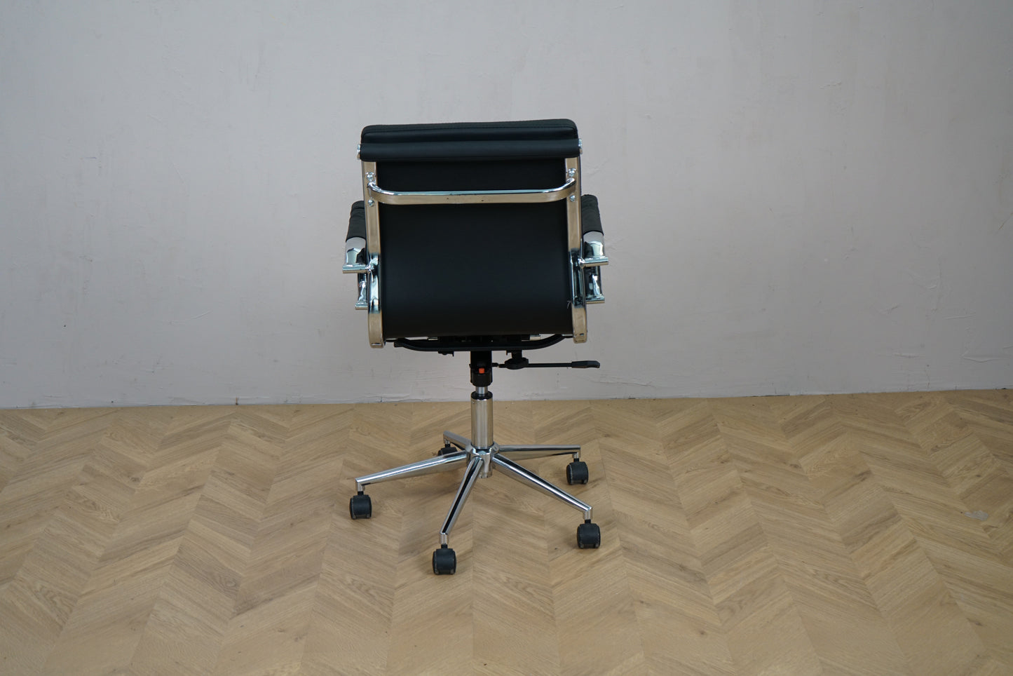 Konferencestol i sort læder set bagfra med krom stel og fodkryds