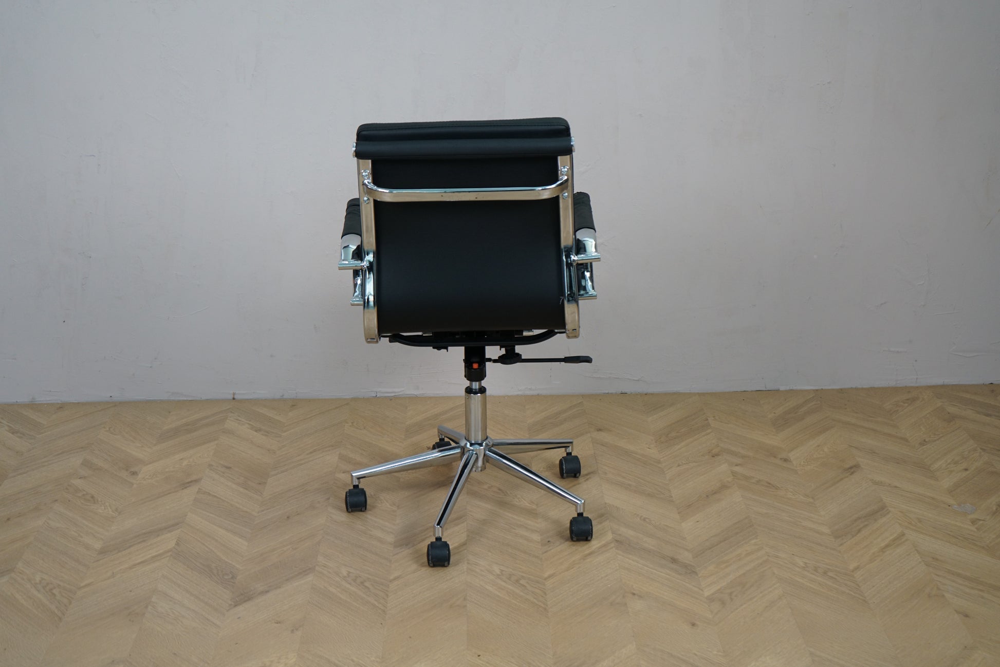 Konferencestol i sort læder set bagfra med krom stel og fodkryds