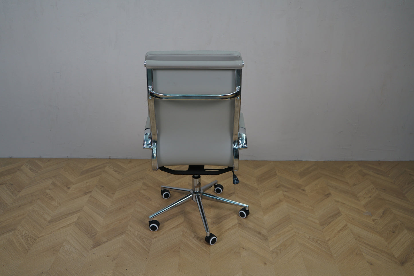Kontorstol i lysegrå kunstlæder set bagfra med krom stel og fodkryds
