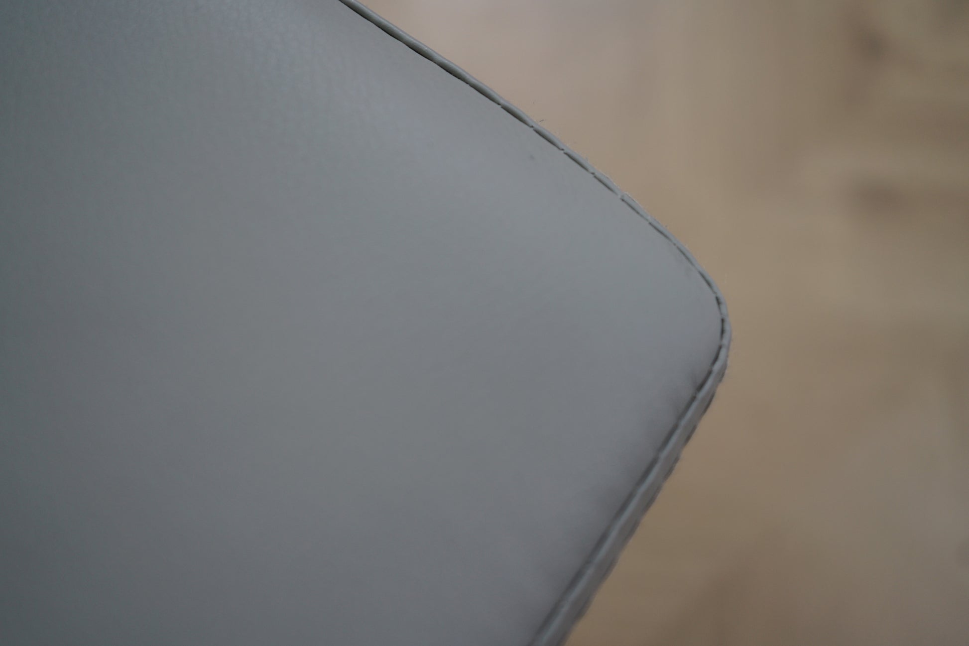 Close-up af lysegrå kunstlæder på kontorstol med fine syninger