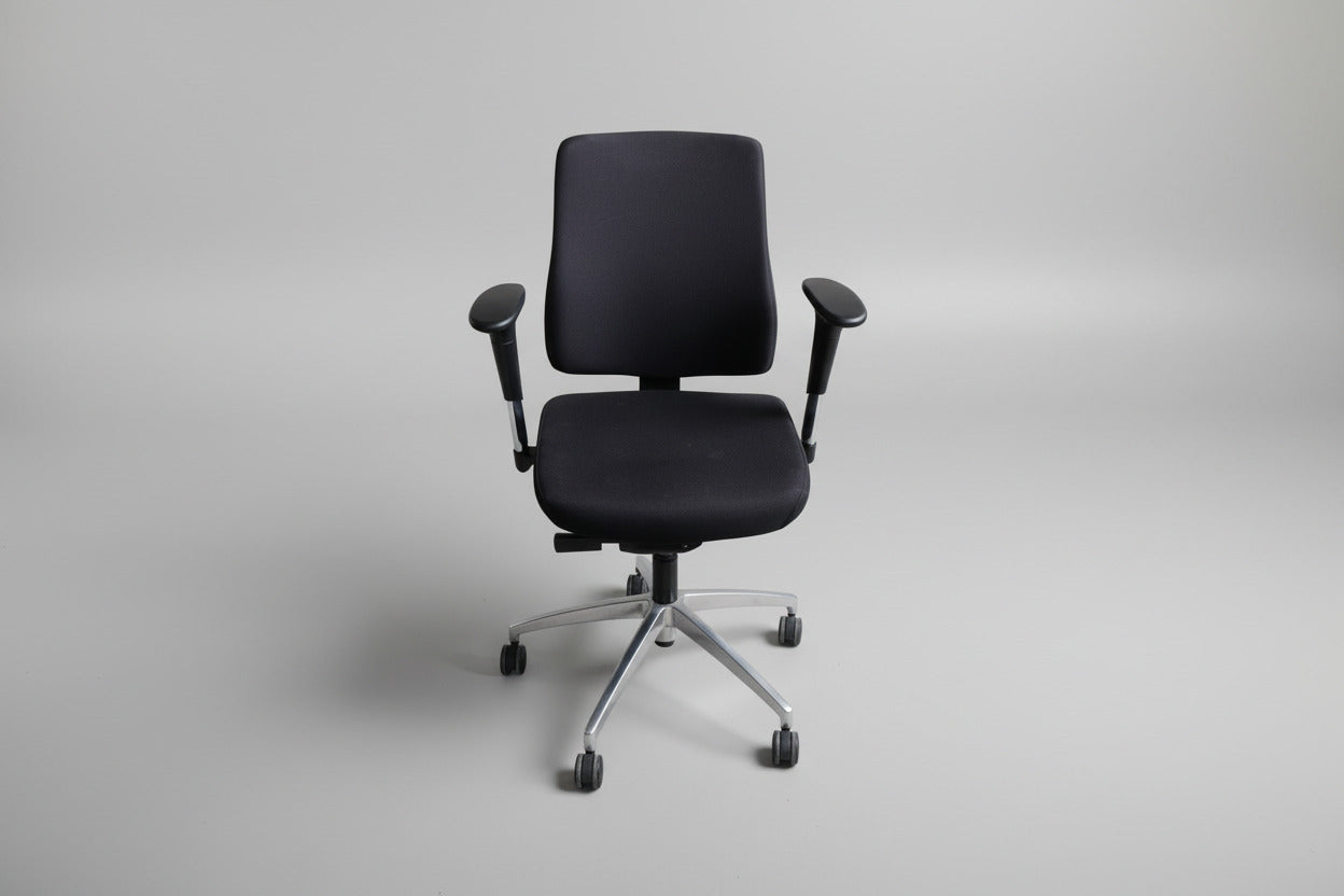 Sort kontorstol i Extreme-stof set forfra med regulerbare armlæn og fodkryds med gummibanehjul.