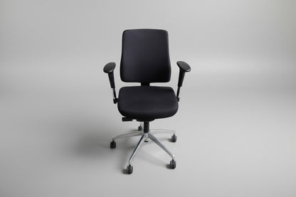 Sort kontorstol i Extreme-stof set forfra med regulerbare armlæn og fodkryds med gummibanehjul.