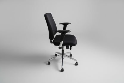 Sort kontorstol set fra siden med regulerbare armlæn, ergonomisk design og gummibanehjul.
