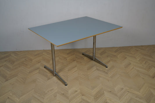 Rektangulært møde- og spisebord med lyseblå laminat og krom ben, set i vinkel