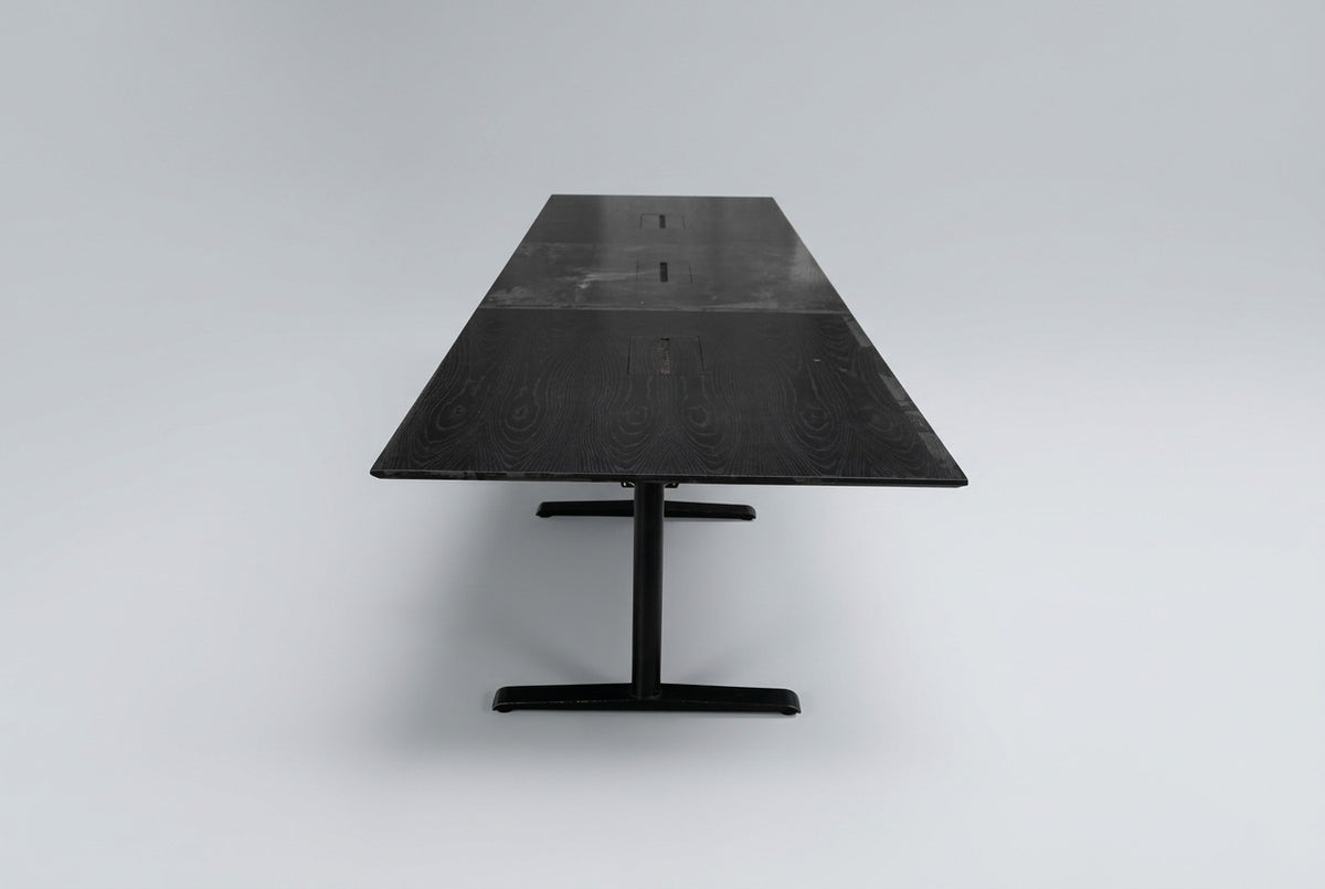 Langt konferencebord i sort eg med sort stel, kabelbakker og affaset bordkant, 500 cm bredt og 73 cm højt, set fra siden.