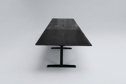 Langt konferencebord i sort eg med sort stel, kabelbakker og affaset bordkant, 500 cm bredt og 73 cm højt, set fra siden.