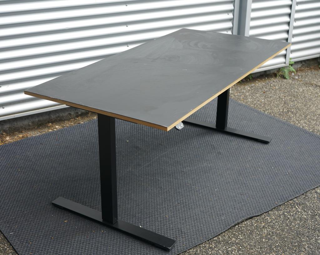Skråt billede af Linak hæve-sænkebord 160x80 med sort linoleum bordplade og birkefinerkanter, elektrisk justerbart skrivebord.