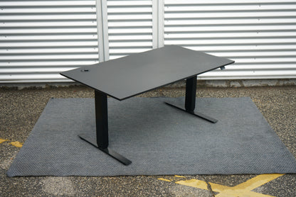 Skrivebord fra Martela set fra skrå vinkel – sort bordplade og stel.