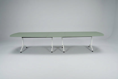 Stort mødebord i salviegrøn linoleum med tøndeformet bordplade, affaset kant og hvidt stel, 400 cm bredt, set forfra.
