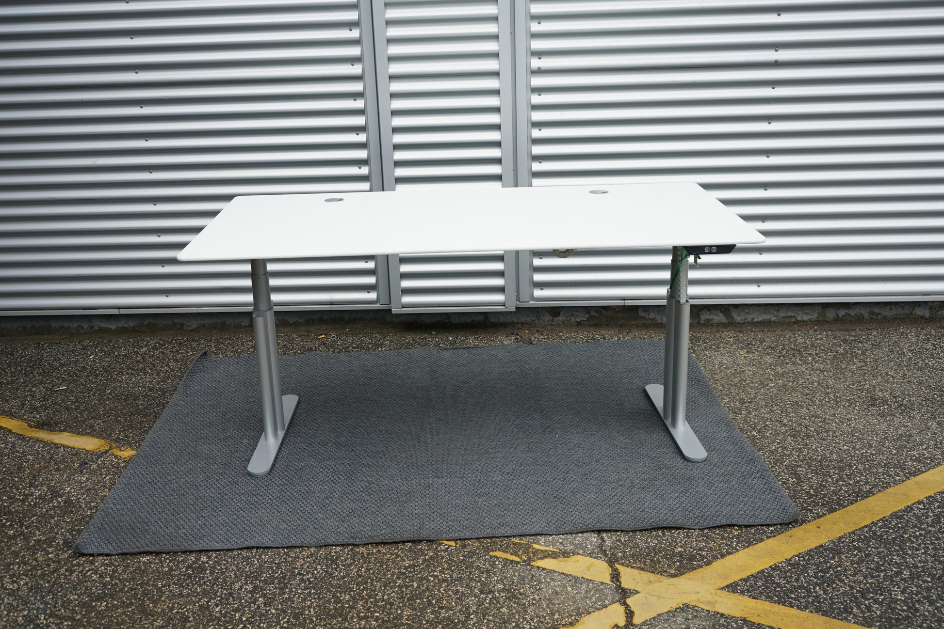 Montana hæve-sænkebord set forfra i hvid med sølvgråt stel og to kabelgennemføringer, 180x90 cm.