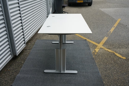 Montana hæve-sænkebord set fra siden med justerbart sølvgråt stel og hvid bordplade, ergonomisk skrivebord 180x90 cm.