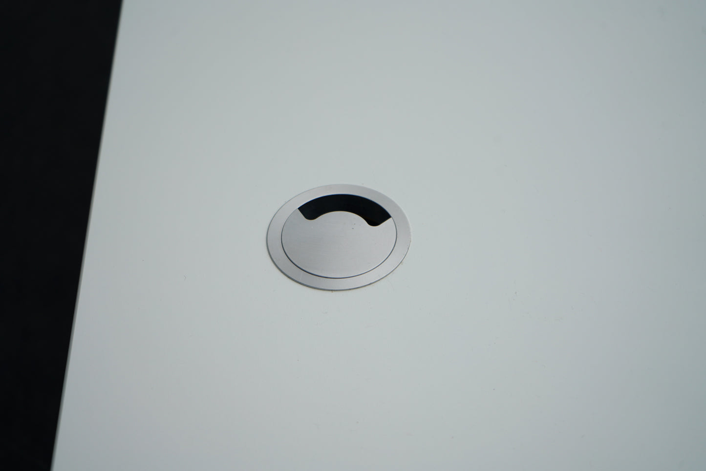 Nærbillede af kabelgennemføring på Montana hæve-sænkebord i hvid, der viser elegant og praktisk ledningsløsning.