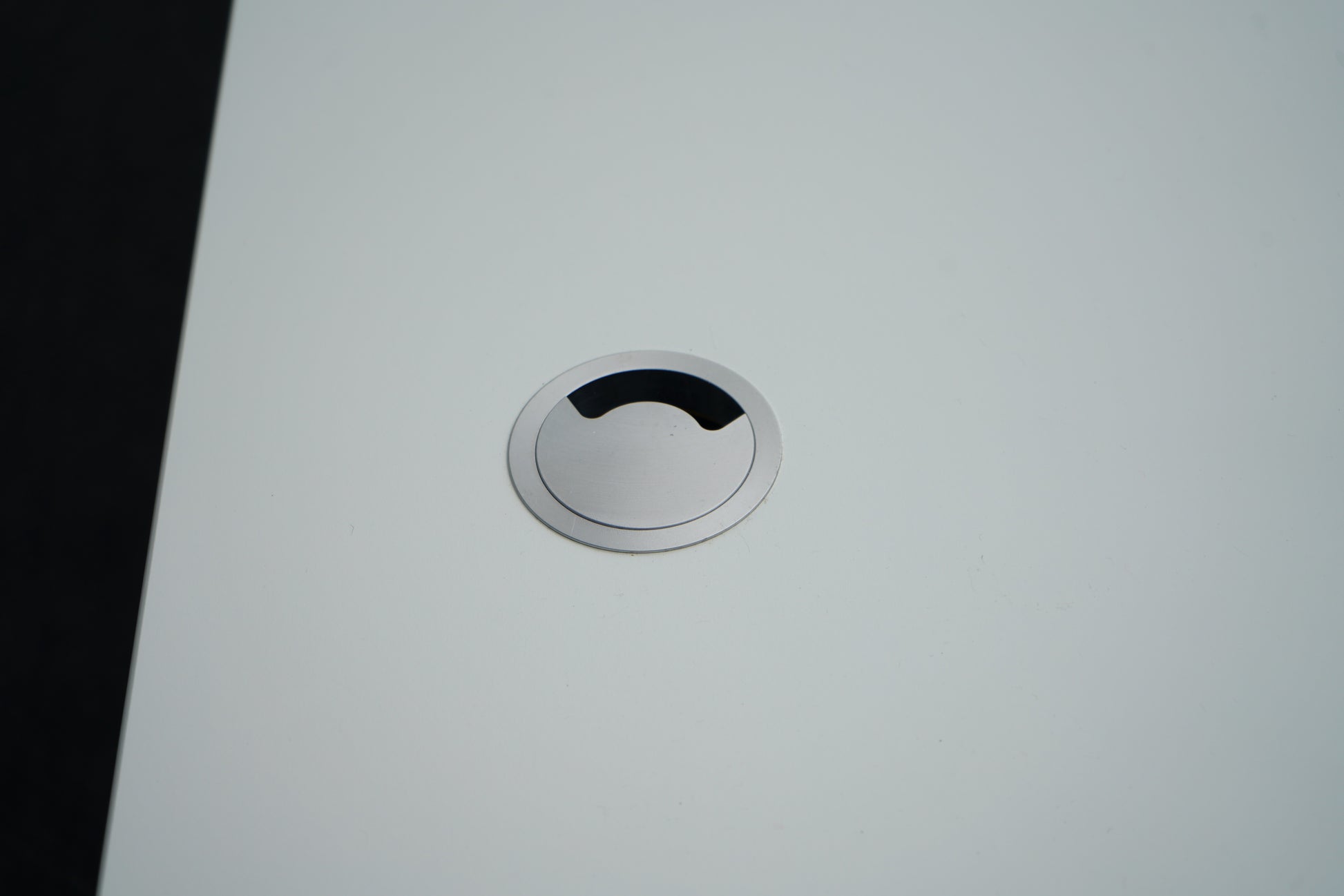 Nærbillede af kabelgennemføring på Montana hæve-sænkebord i hvid, der viser elegant og praktisk ledningsløsning.