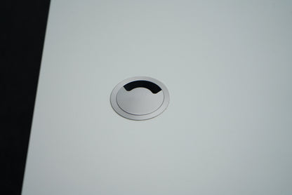 Nærbillede af kabelgennemføring på Montana hæve-sænkebord i hvid, der viser elegant og praktisk ledningsløsning.