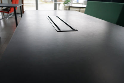 Close-up af sort bordplade og detaljer på Montana mødebord med kabelgennemføring.
