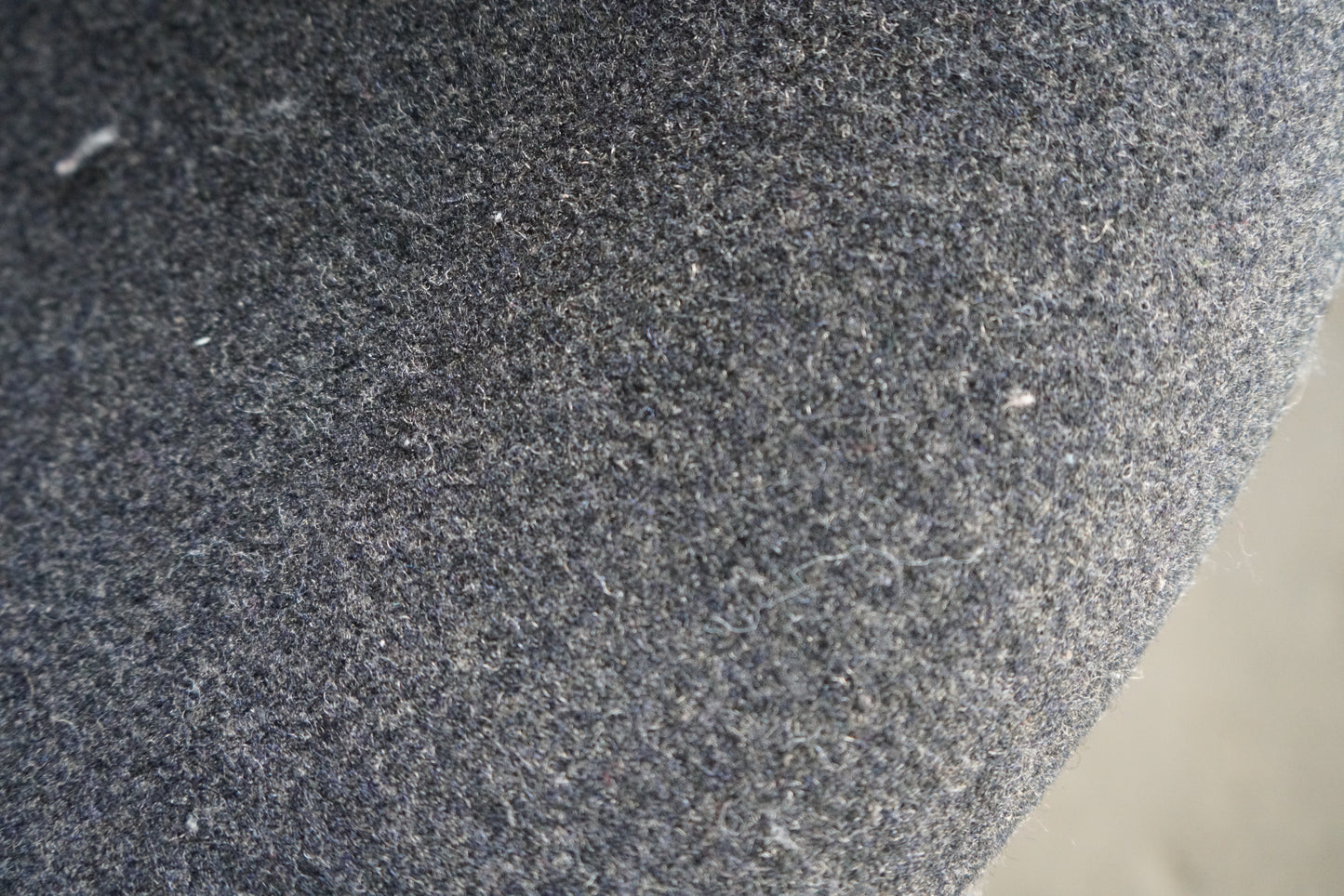 Close-up af grå uldpolstring på Offecct loungestol med stilrent krom stel.