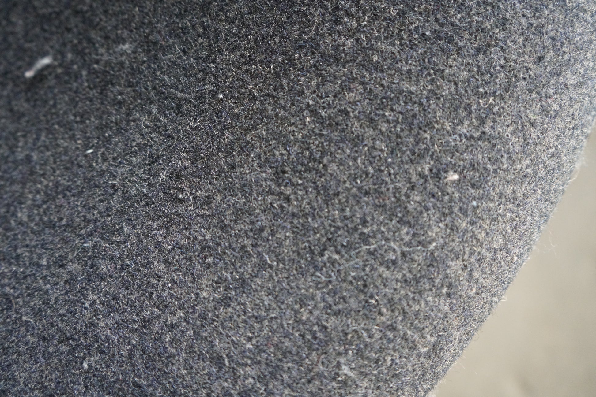 Close-up af grå uldpolstring på Offecct loungestol med stilrent krom stel.