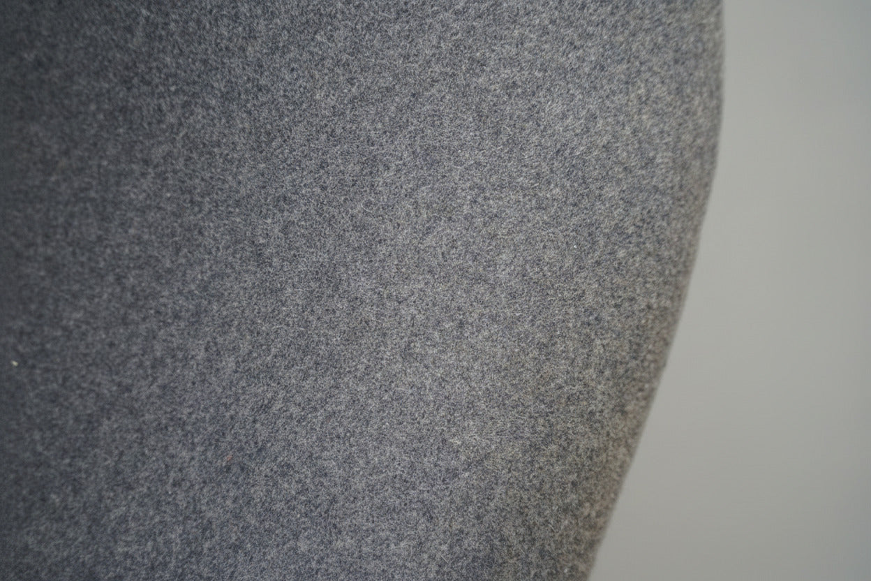 Close-up af lysegrå uldpolstring på Offecct loungestol med elegante detaljer og krom stel.