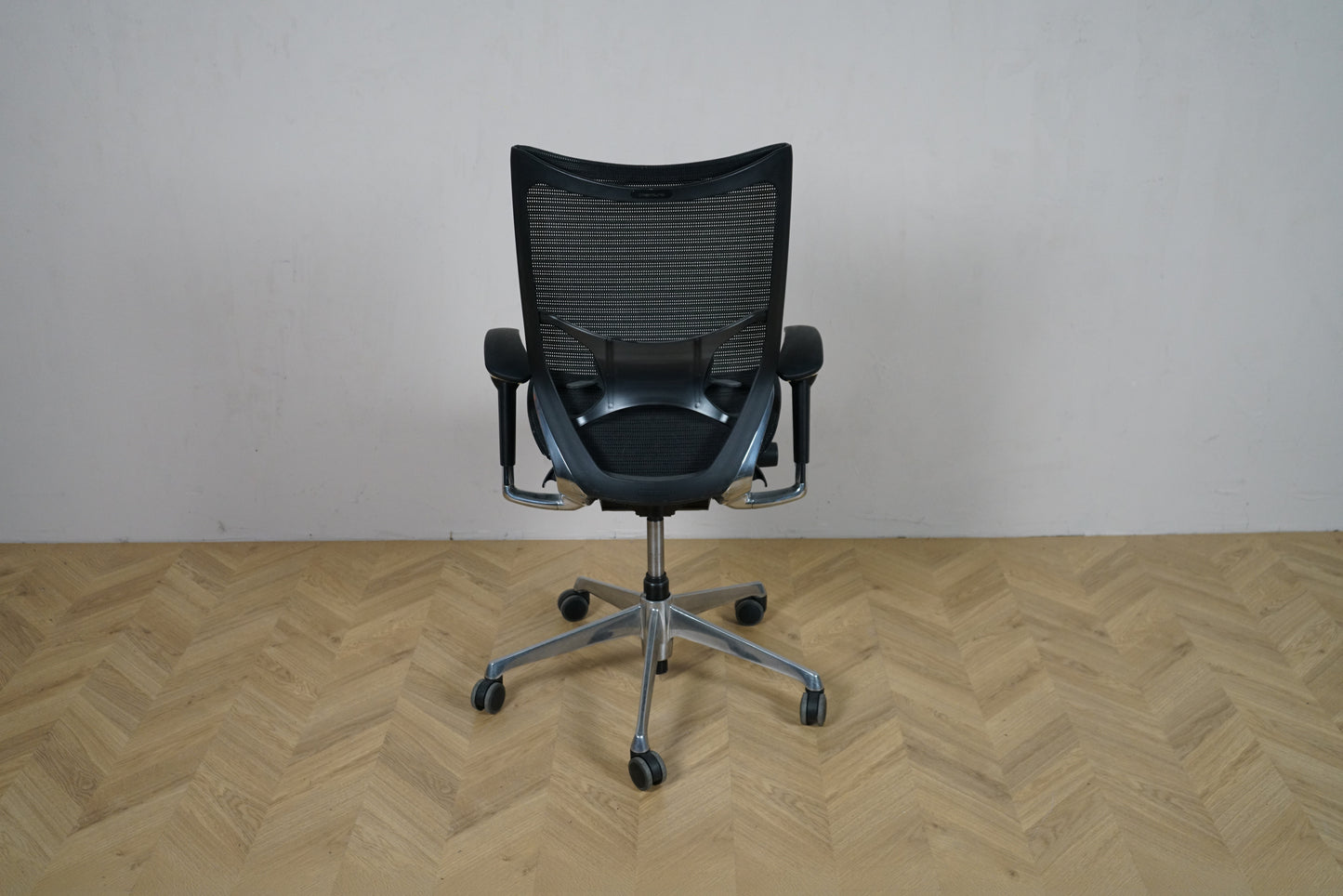 Okamura Baron kontorstol med armlæn set bagfra, med sort mesh-ryg og krom fodkryds.