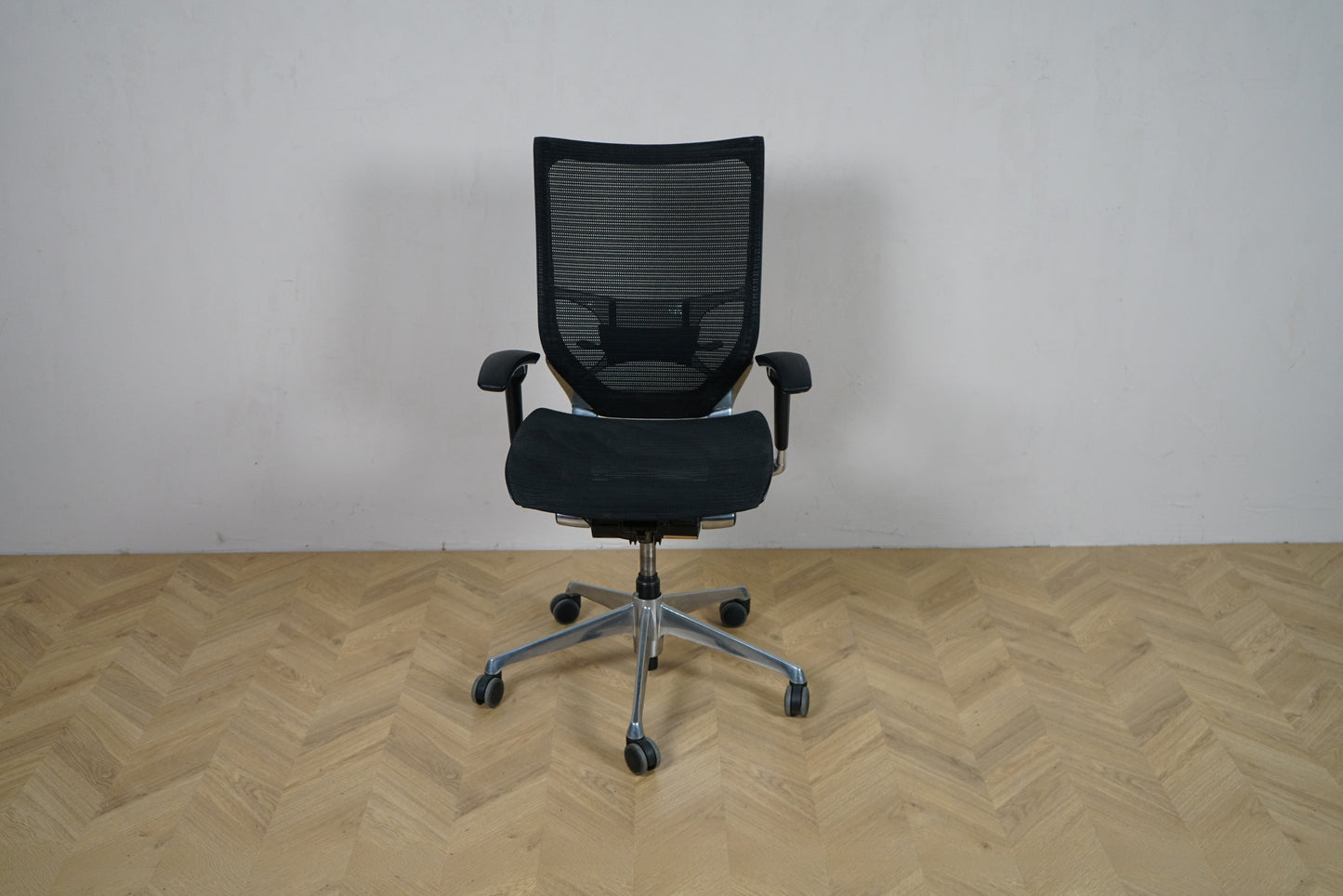 Okamura Baron kontorstol med armlæn set forfra, med sort mesh-ryg og krom fodkryds.