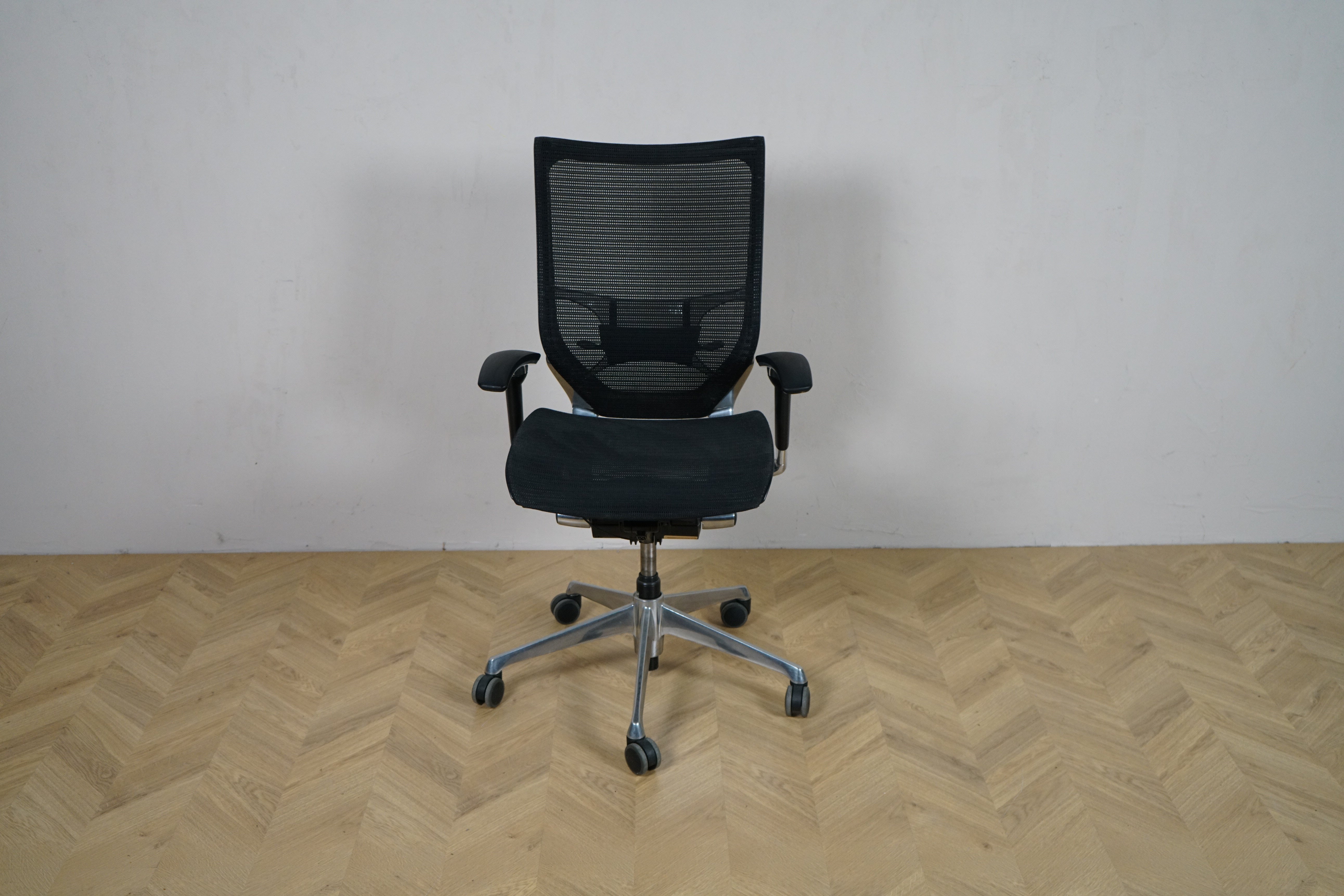Okamura Baron kontorstol med armlæn set forfra, med sort mesh-ryg og krom fodkryds.