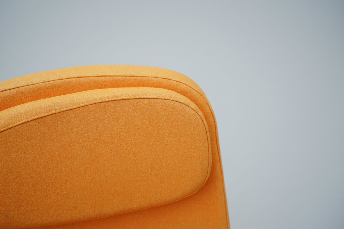 Close up af orange polstret loungestol med armlæn og nakkestøtte