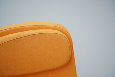 Close up af orange polstret loungestol med armlæn og nakkestøtte