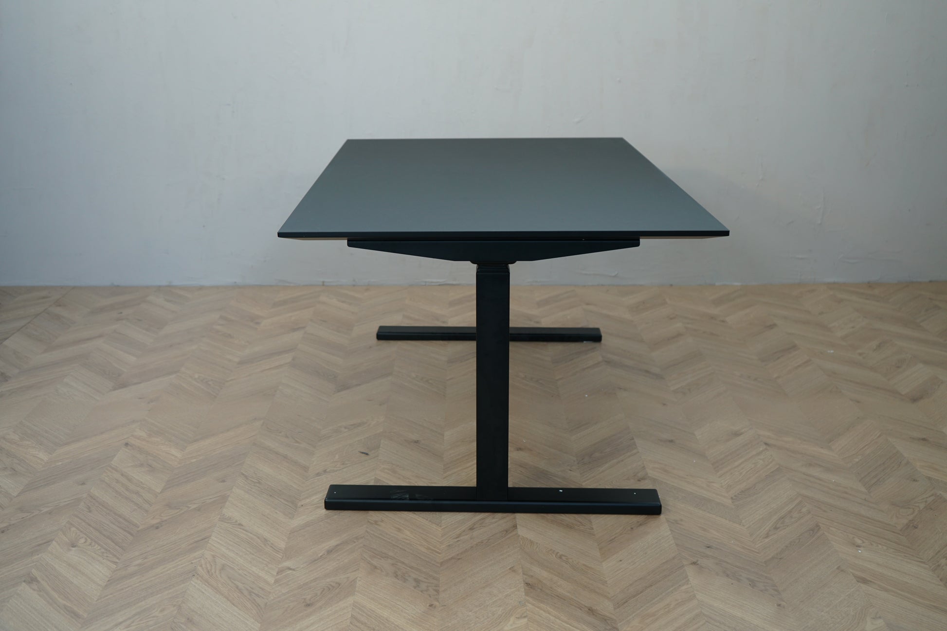Paustian hæve-sænkebord med sort linoleum og sort stel set fra siden.