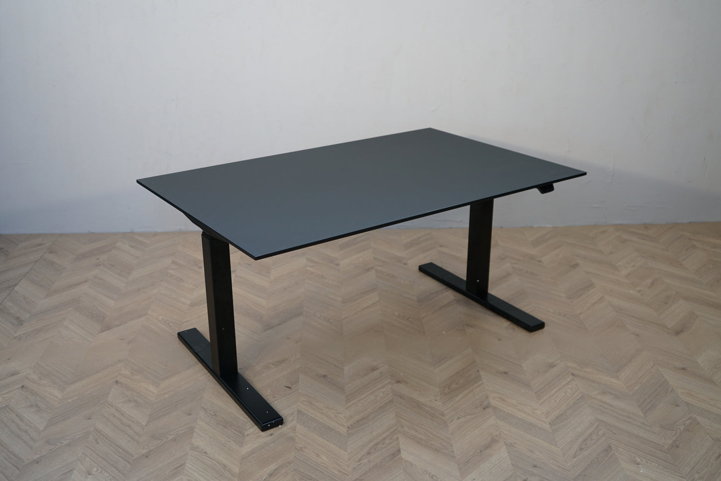 Paustian hæve-sænkebord 140x90 cm med sort linoleum og sort stel set fra skrå vinkel.