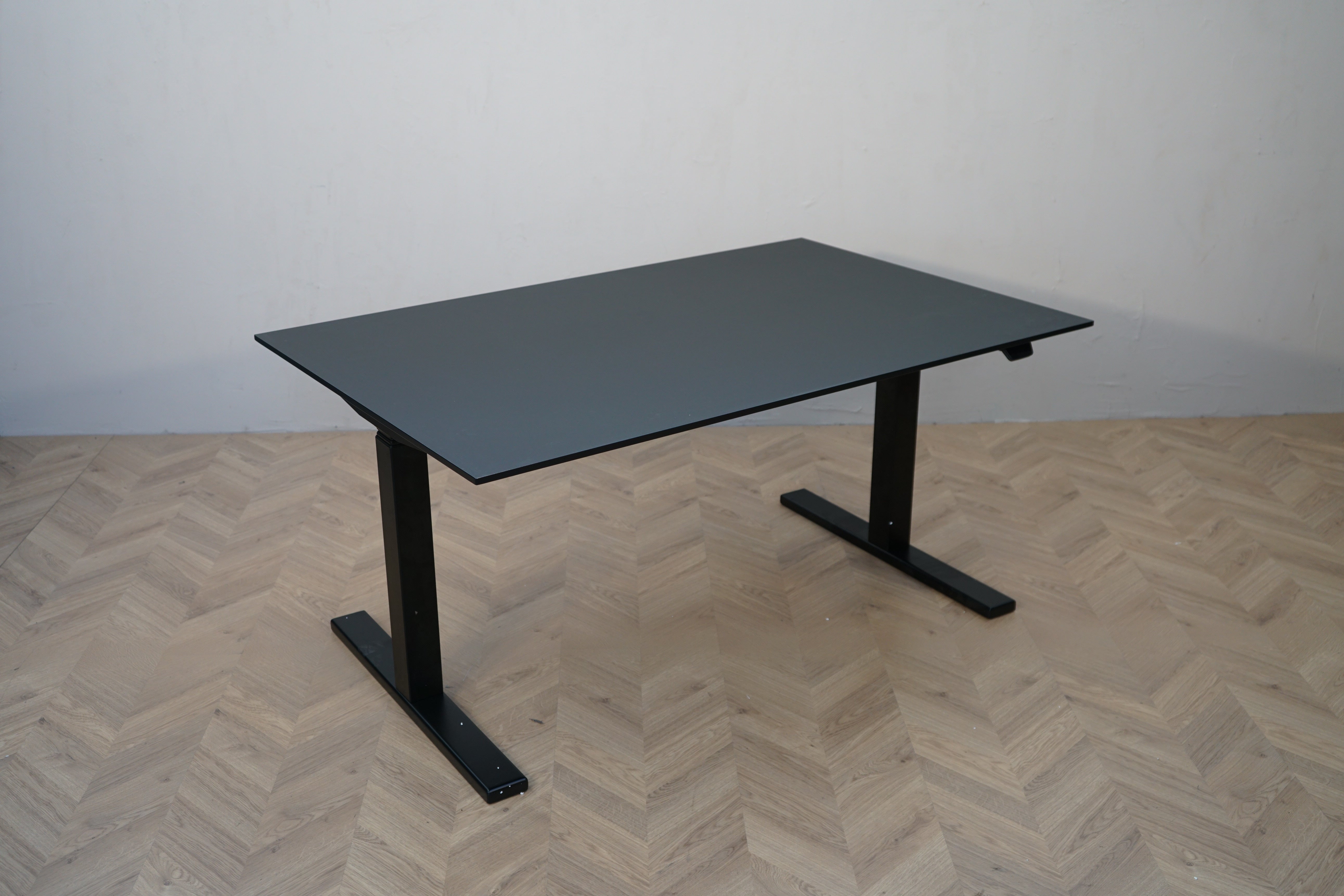 Paustian hæve-sænkebord 140x90 cm med sort linoleum og sort stel set fra skrå vinkel.