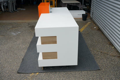 Receptionsbord set fra siden – minimalistisk design i hvid og træ med orange front.