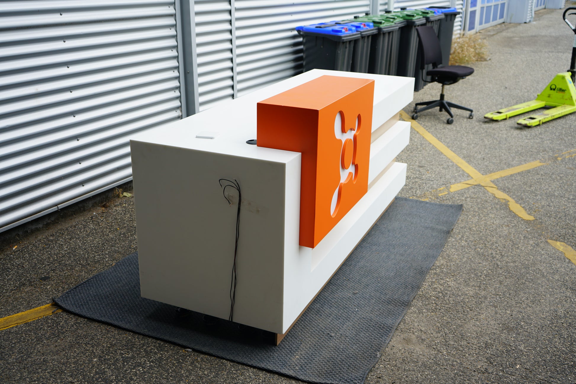 Skrå sidevinkel af receptionsbordet i hvid, træ og orange front.